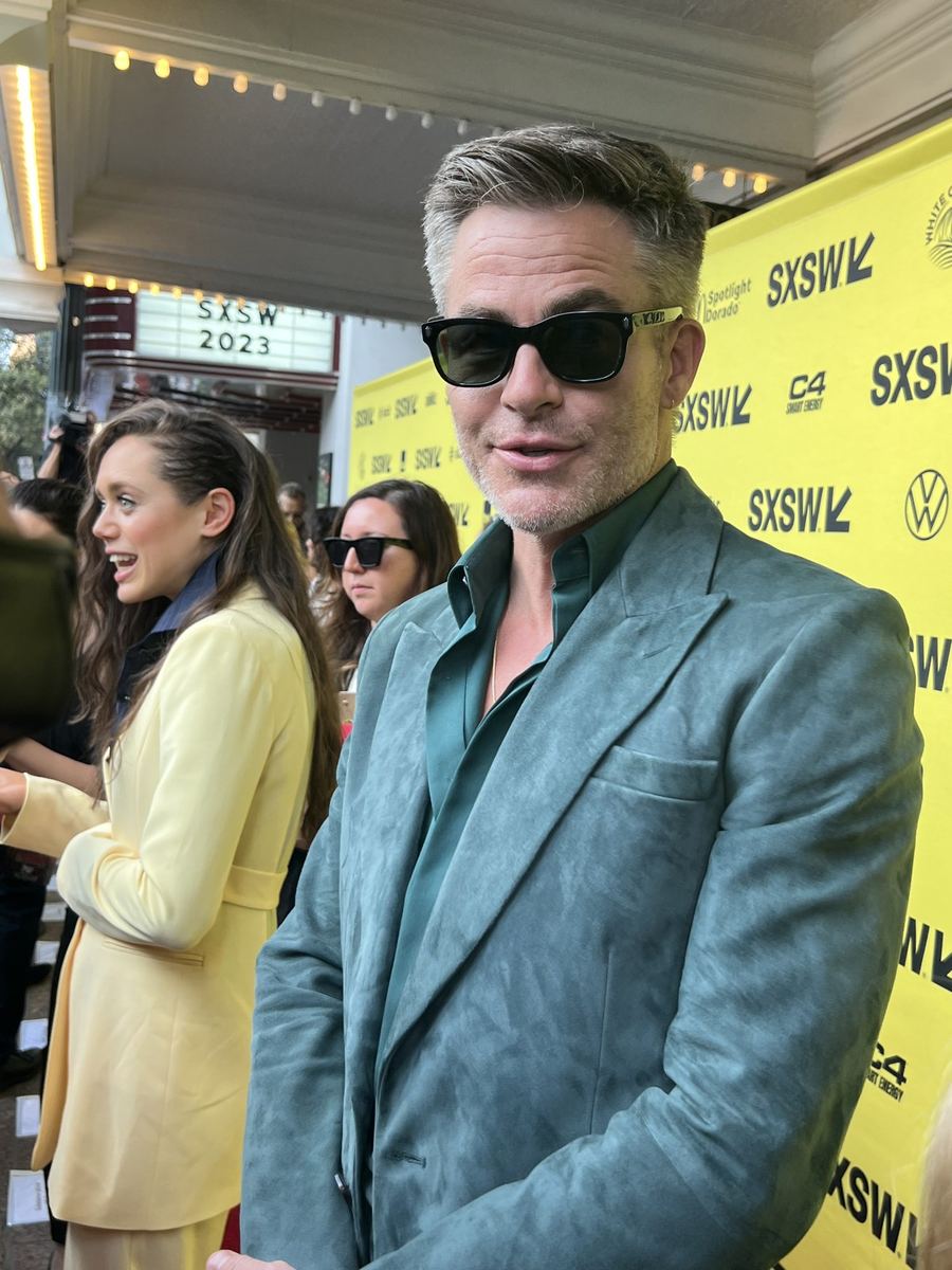 Chris Pine in sunglasses and a grey suit on the SXSW 2023 step-and-repeat.